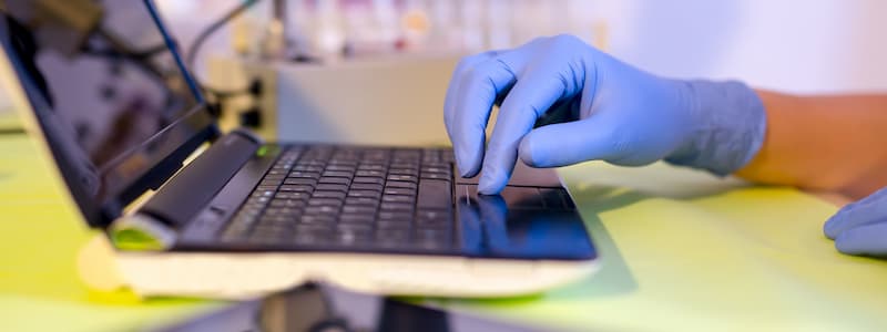 A person using laptop while wearing surgical gloves