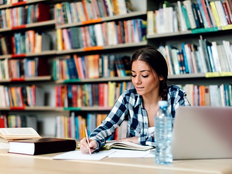A student in a library taking notes.