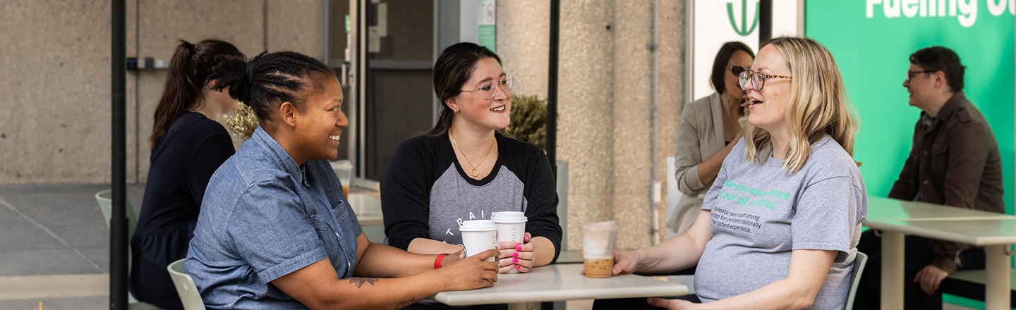 Three students seated at an outdoor cafe