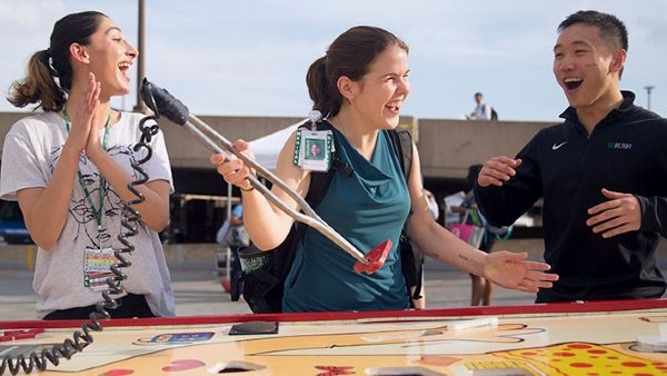 Three students playing an oversized Operation borad game