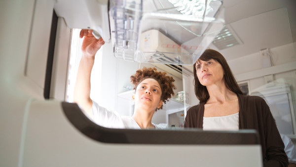 Technician showing mammogram machine to a patient