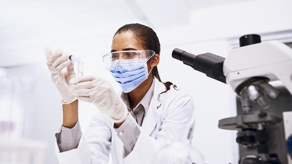 A masked researcher holding a test tube.
